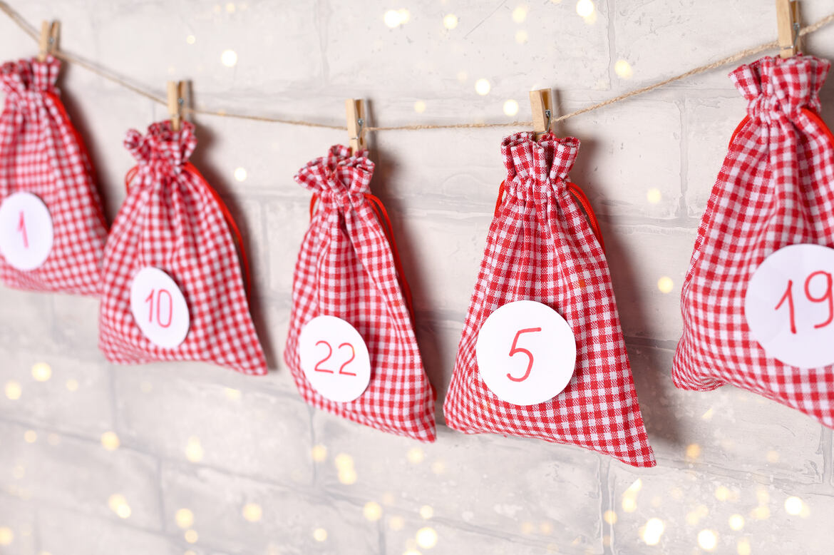Christmas advent calendar. Gift bags hanging on white brick wall. December concept. Selective focus